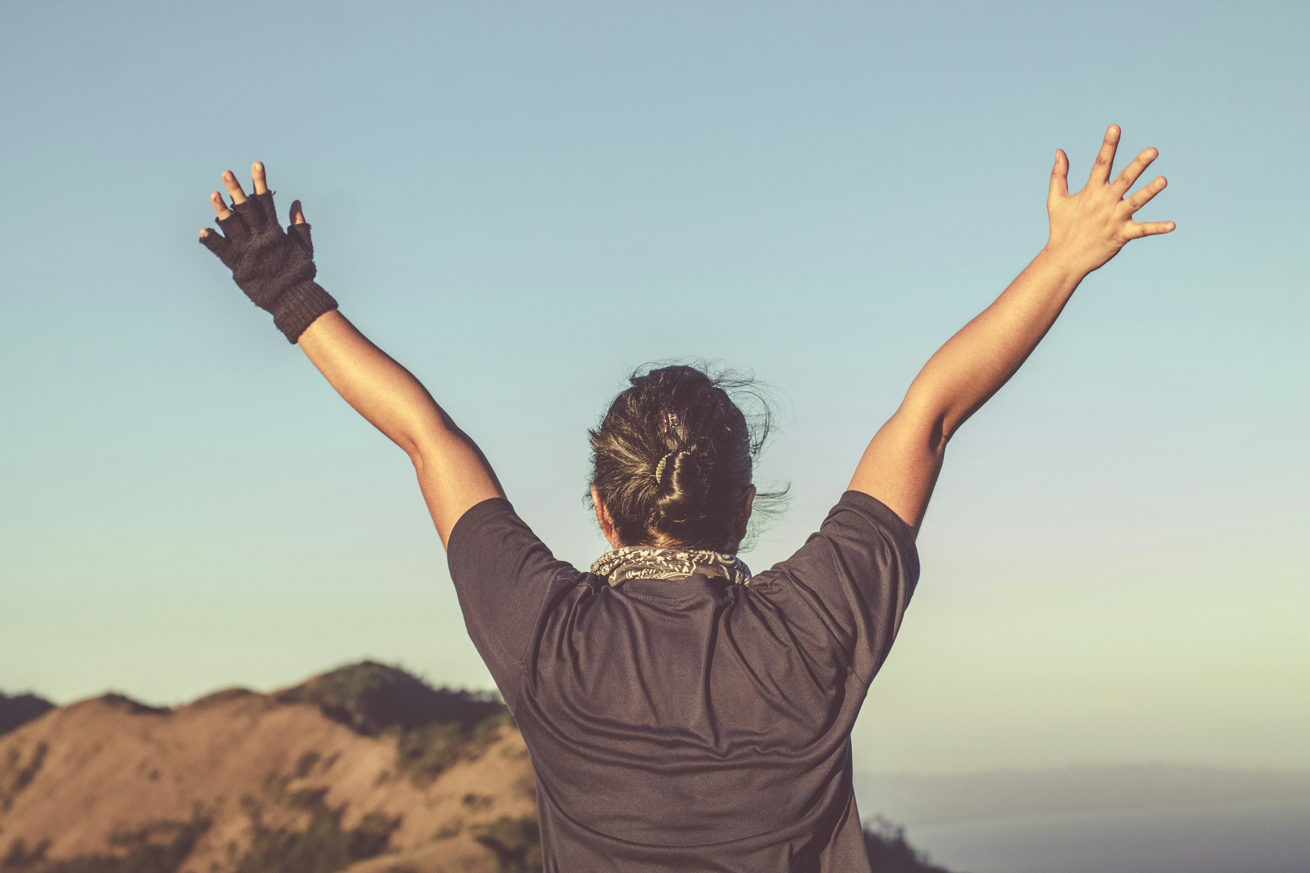 Person with arms raised wide against an open sky — the feeling of going further